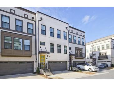 Beautiful townhome exterior with a gray garage, yellow front door, and classic brick and siding details at 1149 Ansel Nw Ln, Atlanta, GA 30318