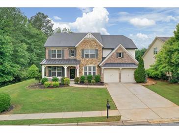 Beautiful two-story home featuring a stone facade, manicured lawn, and attached two car garage at 134 Johnston Farm Ln, Woodstock, GA 30188