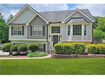 Charming two-story home with well-manicured lawn and lovely landscaping and a combination of light and medium gray siding at 2180 Oakpointe Ct, Buford, GA 30519