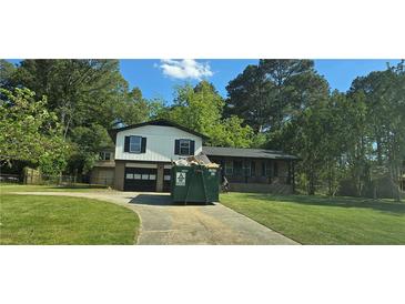 Two story home with a well manicured lawn and a two-car garage, but also a construction dumpster at 382 Plantation Blvd, Lawrenceville, GA 30046