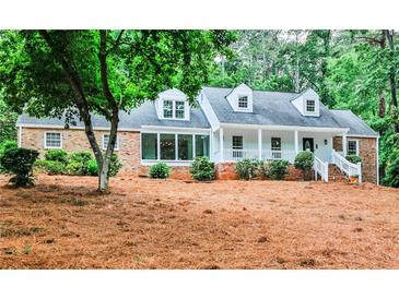 Charming brick and white home with dormer windows and inviting front porch with a landscaped yard at 2244 Deer Ridge Dr, Tucker, GA 30087