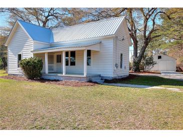Charming white home with a metal roof, inviting front porch, and well-maintained lawn at 6316 Rockland Rd, Lithonia, GA 30038