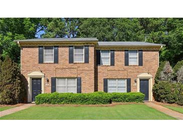 Charming brick townhome with black shutters, green grass, and neatly trimmed bushes at 373 Dixie Ct, Lawrenceville, GA 30046