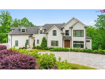 Stunning white exterior with beautiful landscaping and a circular driveway at 1285 Stuart Rdg, Johns Creek, GA 30022