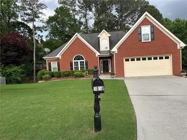 Charming single-Gathering home with a well-manicured lawn, brick facade, and a two-car garage at 1010 Capella Creek Way, Grayson, GA 30017