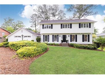 Charming white two-story home with a well-manicured lawn, mature landscaping, and an attached two-car garage at 2730 Burtz Dr, Marietta, GA 30068