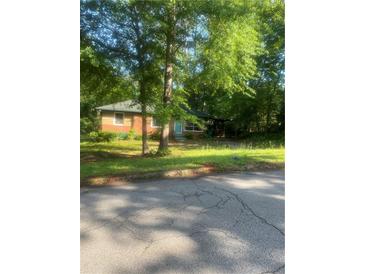 Cozy brick home with a covered carport surrounded by mature trees and a lush green lawn at 3178 Beech Dr, Decatur, GA 30032