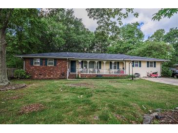 Charming single-story home with a brick accent and welcoming front porch, surrounded by mature trees and a lush green lawn at 8053 Duralee Ln, Douglasville, GA 30134