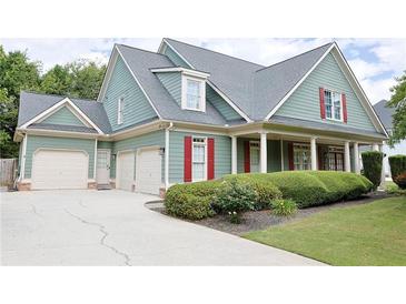Charming home featuring a three-car garage, beautifully landscaped yard, and inviting covered porch at 330 Bay Grove Rd, Loganville, GA 30052