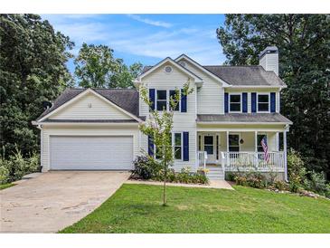 Charming two-story home featuring a manicured lawn, attached garage, and inviting front porch at 7155 Bannister Park Ln, Cumming, GA 30028