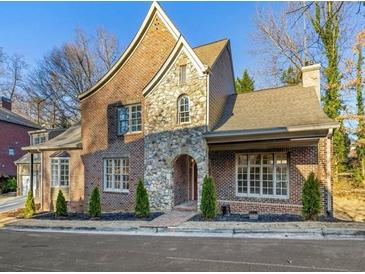 Charming brick and stone home featuring an arched entryway, manicured landscaping, and a classic architectural design at 580 Cliftwood Ct, Sandy Springs, GA 30328