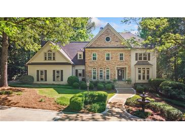 Beautiful stone and stucco home with manicured landscaping and a charming fountain in a circular driveway at 1240 Bridgewater Walk, Snellville, GA 30078