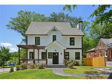Charming two-story home with a manicured lawn, stone walkway, and a lovely pergola covered porch at 1059 Woodland Ave, Atlanta, GA 30316