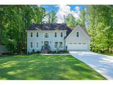 Charming home with a manicured lawn, gray stucco, blue front door, and a two-car garage at 3295 Waters Ml, Alpharetta, GA 30022