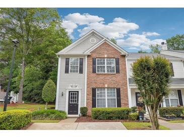 Charming two-story townhome featuring brick and gray siding, complemented by manicured landscaping and black shutters at 9165 Nesbit Ferry Rd # 9, Alpharetta, GA 30022