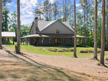 Charming home featuring a welcoming wrap-around porch and lush, green landscaping at 3805 Carder Ln, Cumming, GA 30028