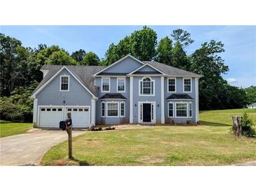 Charming two-story home featuring a two-car garage and a well-manicured lawn at 6231 Waterton Way, Lithonia, GA 30058