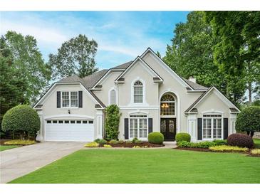 Charming traditional home featuring a manicured lawn, lush landscaping, and a welcoming two-car garage at 725 Heathland Dr, Roswell, GA 30075