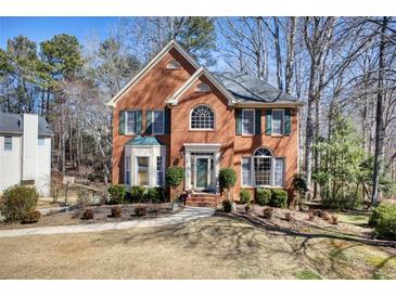 Charming brick home featuring lush landscaping and classic architectural details, with mature trees surrounding the property at 9600 Poplar Ct, Douglasville, GA 30135