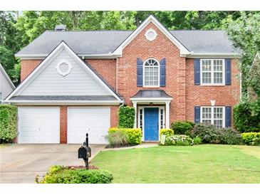 Charming brick home featuring a manicured lawn, blue door, and a two-car garage at 3168 Kirkwood Nw Dr, Kennesaw, GA 30144