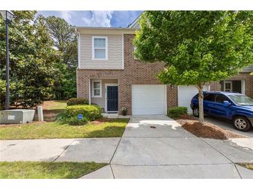 Charming two-story townhome with brick and siding, featuring an attached garage and well-maintained front yard at 2033 Millstream Holw, Conyers, GA 30012