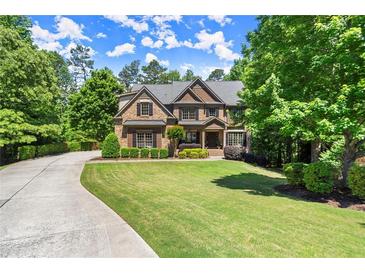 Stunning brick home with lush landscaping, sprawling green lawn, and long private driveway at 2660 Burnt Hickory Dr, Cumming, GA 30028