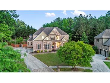Beautiful brick and stone home with manicured lawn, mature trees, and inviting curb appeal at 3302 Anna Ruby Ln, Buford, GA 30519