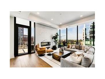 Bright living room with hardwood floors, modern furniture, fireplace, and floor to ceiling windows with city views at 40 12Th Ne St # 1406, Atlanta, GA 30309