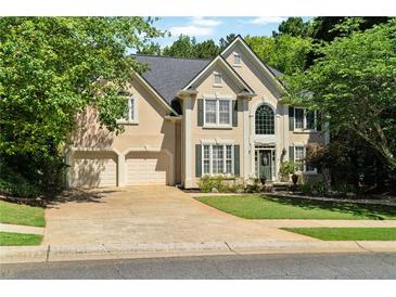 Charming two-story home featuring a three-car garage, lush lawn, and manicured landscaping at 902 Laurel Crest Dr, Woodstock, GA 30189