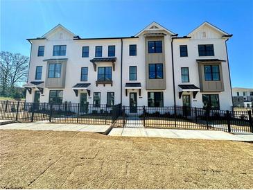 Beautiful, modern townhouse exterior with black trim, white brick, black iron fence, and manicured landscaping at 508 Healy Dr # 70, Cumming, GA 30040