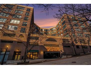 Beautiful brick apartment building features a street view with a garage and sunset background at 115 W Peachtree Nw Pl # 713, Atlanta, GA 30313