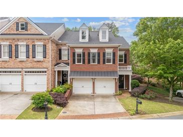Beautiful brick townhome featuring a two-car garage, manicured landscaping, and a classic architectural design at 11945 Dancliff Trce, Alpharetta, GA 30009