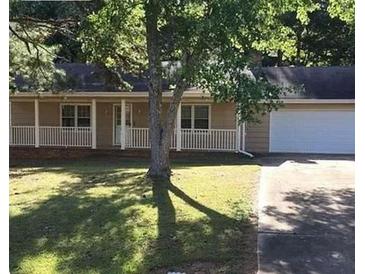 Charming single-story home with a white picket fence and an attached two car garage nestled among mature trees at 1111 Louise Se Ct, Conyers, GA 30013