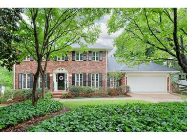 Charming two-story brick home with a manicured lawn, black shutters, and mature trees providing shade at 4140 Summit Dr, Marietta, GA 30068