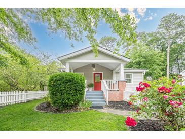 Charming home featuring a bright red front door, a lovely green lawn, and a white picket fence at 2497 Edwards Nw Dr, Atlanta, GA 30318
