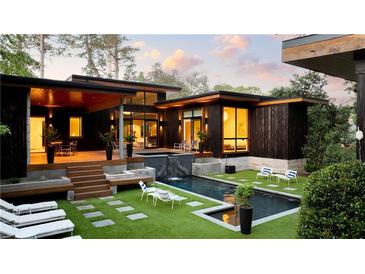 This modern home features a luxurious backyard with a sleek pool, waterfall, and ample seating at 3740 Powers Ferry Nw Rd, Atlanta, GA 30342