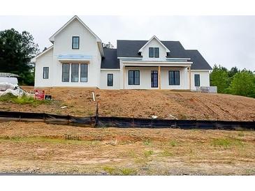 Elegant two-story home featuring a modern farmhouse design and a covered porch entry at 933 Mount Carmel Church Ln, Canton, GA 30114