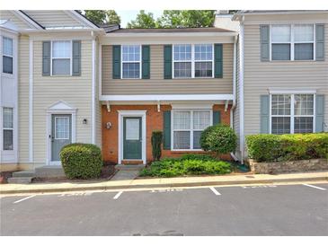 Inviting townhouse featuring a brick facade, green shutters and door, complemented by lush landscaping at 1295 Kilmington Ct, Alpharetta, GA 30009