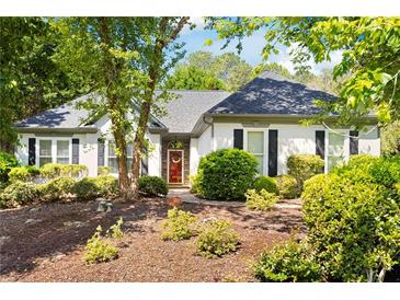 Charming single-story home featuring a well-manicured front yard with lush landscaping and a welcoming red front door at 401 Azalea Cv, Canton, GA 30114