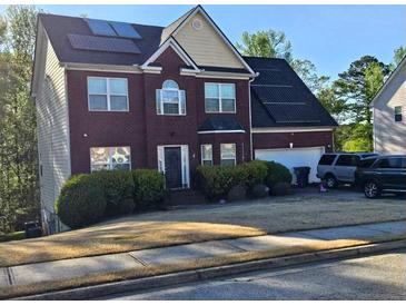 Charming two-story brick home featuring solar panels, a two-car garage, and well-maintained landscaping at 230 Shiver Blvd, Covington, GA 30016