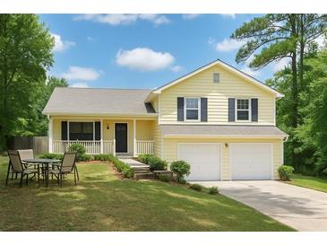 Charming yellow two-story home with a well-manicured lawn, a two-car garage, and a cozy front porch, perfect for suburban living at 309 Carmen Ct, Lawrenceville, GA 30046