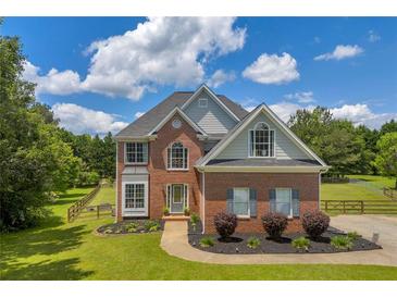 Charming two-story brick home with a manicured lawn and professional landscaping at 3135 Castlewood Dr, Loganville, GA 30052