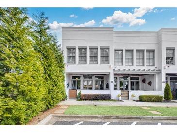 Charming two-story townhome with white painted brick, manicured lawn and landscaped garden at 212 Sessions St, Woodstock, GA 30188