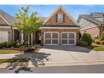 Charming brick home featuring a two-car garage and manicured landscaping, creating an inviting curb appeal at 5850 Overlook Rdg, Suwanee, GA 30024