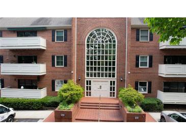 Brick condo building with large arched window, manicured landscaping, and covered balconies provides inviting curb appeal at 107 Ridley Howard Ct, Decatur, GA 30030