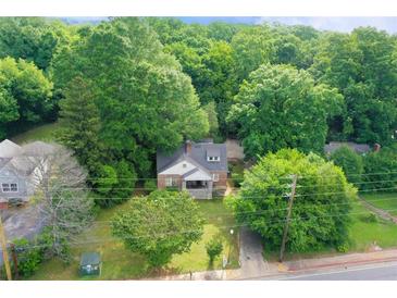 Aerial view of a charming two-story home with a front porch nestled among lush greenery and mature trees at 338 Candler Rd, Atlanta, GA 30317