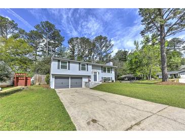 Split-level home features gray siding, an attached two-car garage, and a well-maintained lawn and driveway at 1460 Parkmont Dr, Roswell, GA 30076