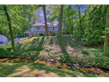 Charming two-story home featuring a stone facade, red door, and lush greenery at 2162 Brookview Nw Dr, Atlanta, GA 30318