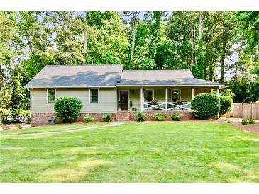 Charming single-story home with a well-manicured lawn, inviting porch, and mature trees, offering a serene curb appeal at 3255 Sutcliffe Nw Rdg, Marietta, GA 30064