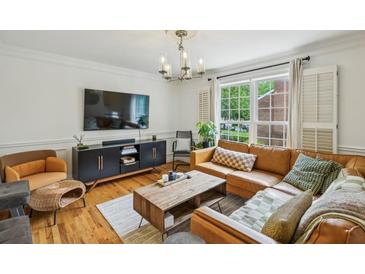 Bright living room features a brown leather sofa, modern lighting, and a view to the outside at 1634 Ponce De Leon Ne Ave # 208, Atlanta, GA 30307